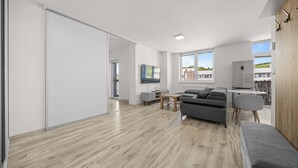 A modern living space with a sliding door, a grey sofa, a small table, and a view of the outside. - 2 room Apartment with balcony-Nálepkova (Liptovský Mikuláš)