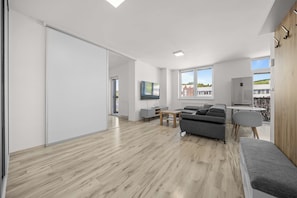 Ein modernes Wohnzimmer mit einer Schiebetür, einem grauen Sofa, einem kleinen Tisch und Blick ins Freie.