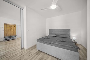 Een moderne slaapkamer met een bed, een plafondventilator en een houten garderobe.
