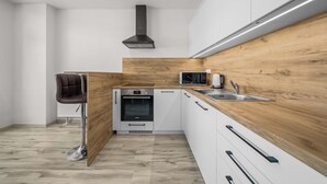 A modern kitchen with a Bosch oven, a microwave, and a sink. - 2 room Apartment with balcony-Nálepkova (Liptovský Mikuláš)