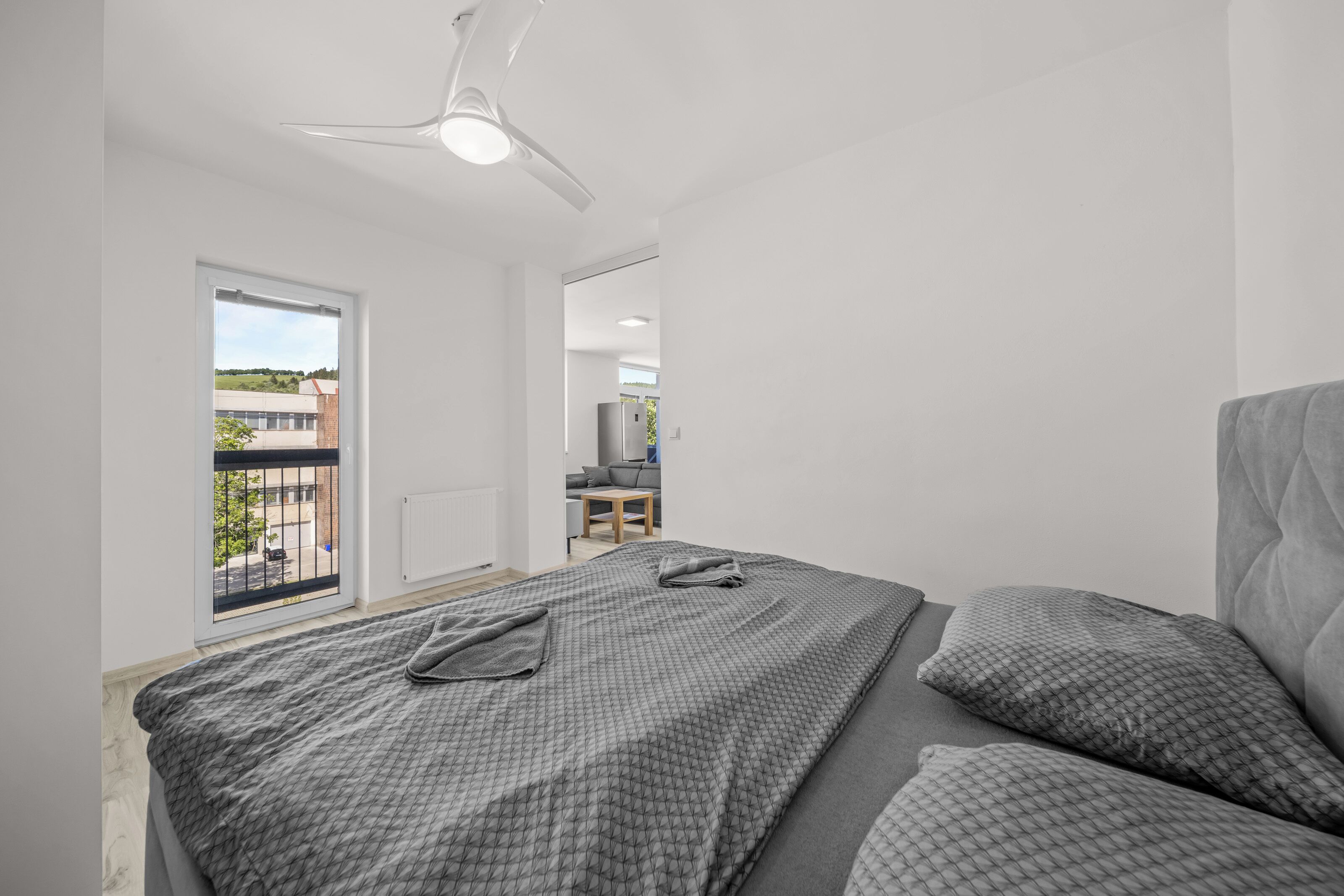 Une chambre à coucher avec un lit, un ventilateur de plafond et une vue sur l’extérieur.