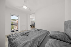 A bedroom with a bed, a ceiling fan, and a view of the outside. - 2 room Apartment with balcony-Nálepkova (Liptovský Mikuláš)