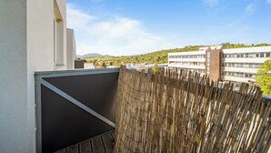 A balcony with a view of a residential area, a bamboo fence, and a building with multiple windows. - 2 room Apartment with balcony-Nálepkova (Liptovský Mikuláš)
