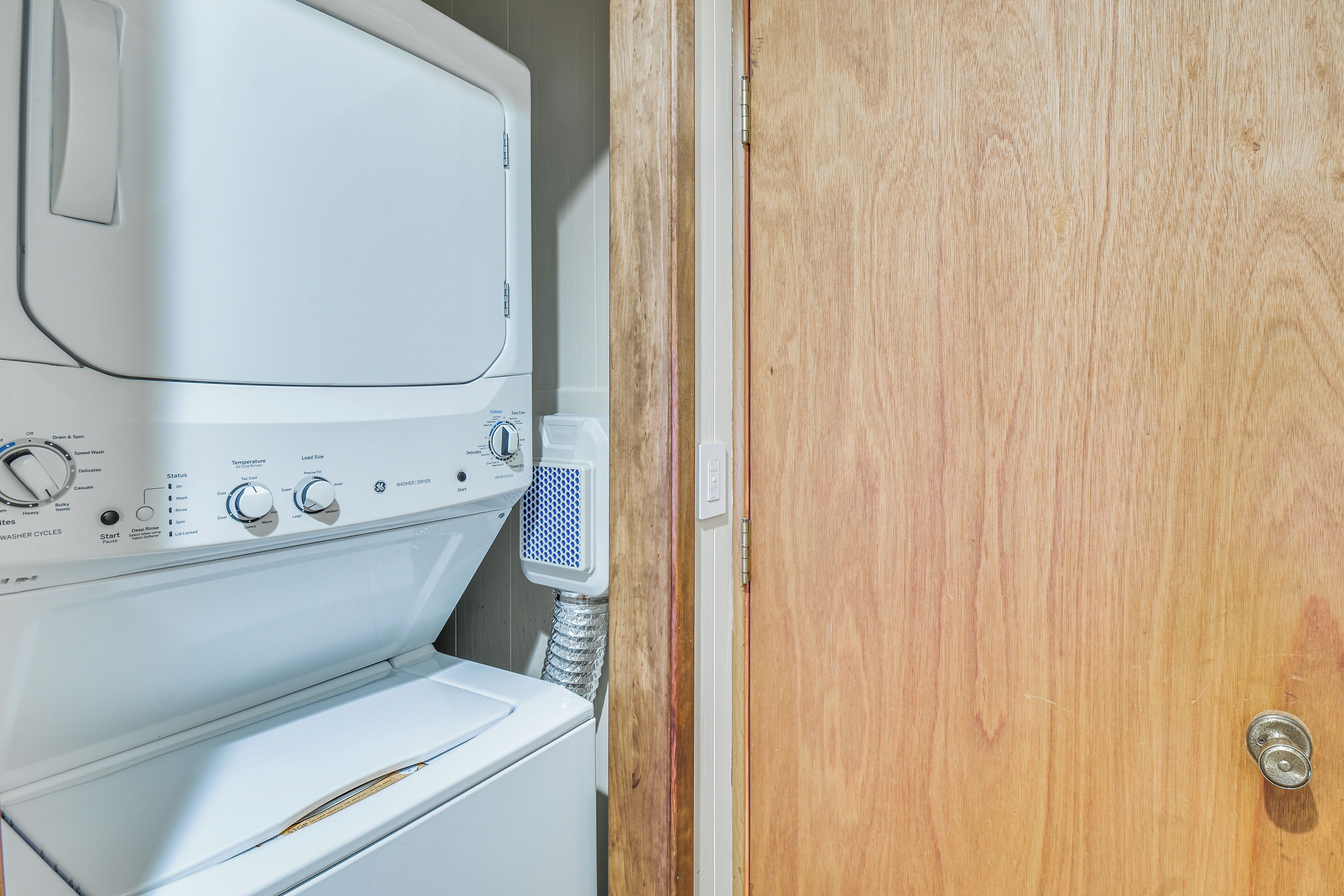 A white washing machine and dryer in a room with a wooden door.