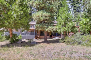 A two-story house with a covered porch, surrounded by trees and a dry grassy area.