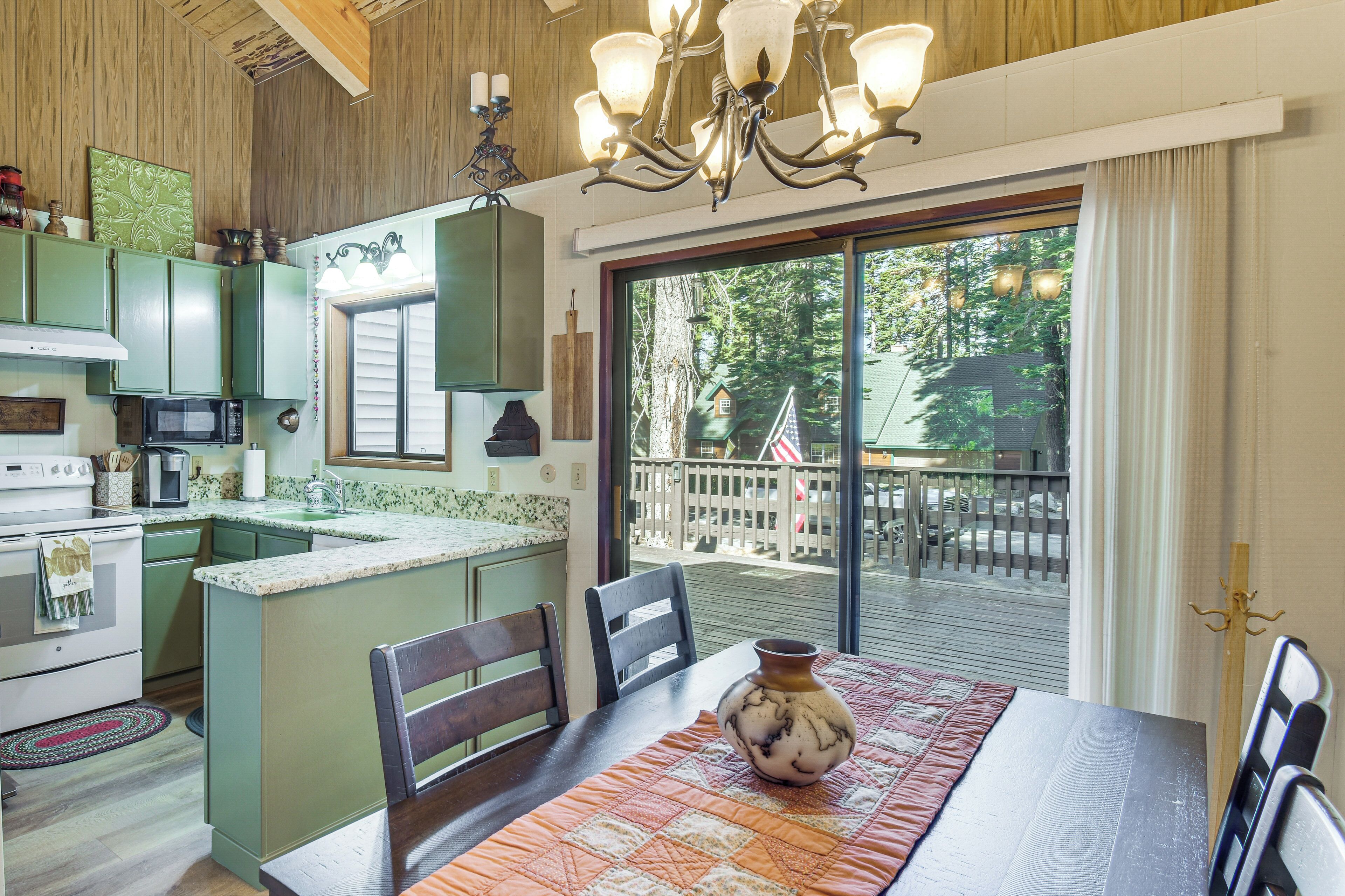 A kitchen with a central island, wooden cabinets, and a dining area with a table and chairs.
