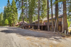 A rustic lodge with multiple wooden buildings, a gravel driveway, and tall pine trees surrounding the area.
