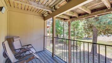 A covered outdoor seating area with metal chairs and a wooden deck.