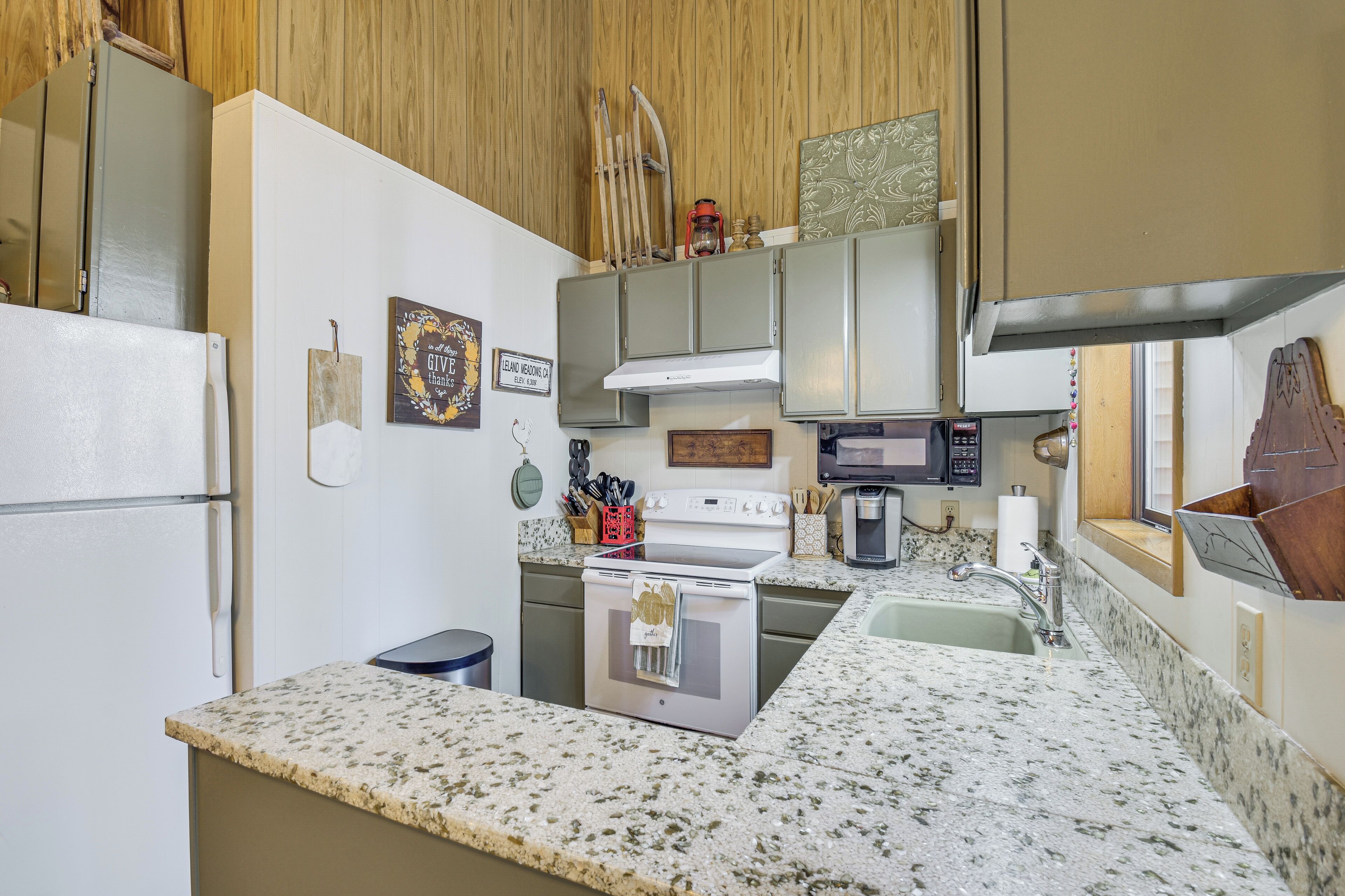 A kitchen with a refrigerator, stove, microwave, and granite countertop.