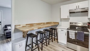 A compact kitchen with a wooden countertop, bar stools, a stainless steel oven, and white cabinetry. - Walk to FSU Campus & Stadium! Tallahassee Home (Tallahassee)
