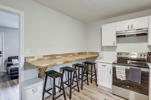 A compact kitchen with a wooden countertop, bar stools, a stainless steel oven, and white cabinetry. - Walk to FSU Campus & Stadium! Tallahassee Home (Tallahassee)