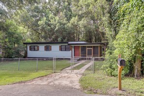 A single-story house with a front porch, a mailbox, and a chain-link fence.
