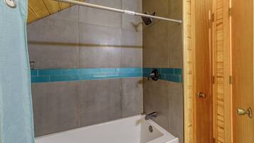 Ein Badezimmer mit Badewanne, Duschkopf und Holztür.