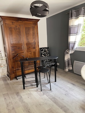 A room with a wooden wardrobe, a black metal table with two chairs, a black and white patterned chair, and a window with curtains. - Cozy room with separate entrance (Cornebarrieu)