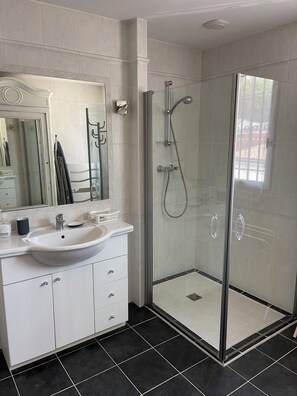 Une salle de bain moderne avec une douche à parois de verre, un lavabo blanc et un grand miroir.