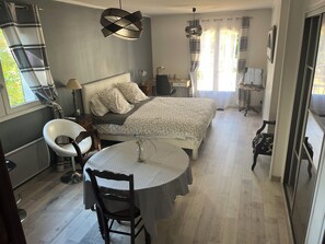 Une chambre à coucher comprenant un lit, des tables de chevet, un bureau, une chaise et une table à manger.