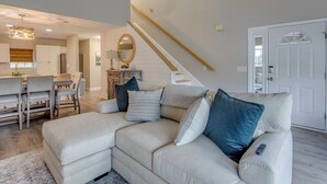 A living room with a sectional sofa, a dining area, and a staircase. - Ocean-view Retreat Near Barefoot Landing & Beach! (Myrtle Beach)