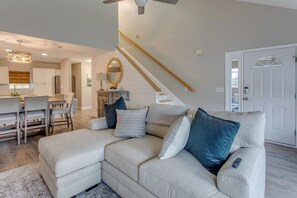 Ein Wohnzimmer mit Ecksofa, Essbereich und einer Treppe.
