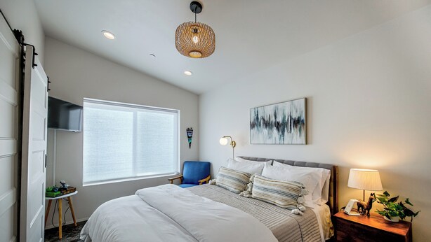 Une chambre à coucher avec un grand lit, un bureau, une chaise, une lampe et un tableau au mur.