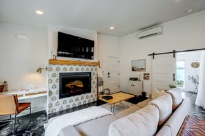 Ein modernes Wohnzimmer mit Kamin, Fernseher und einer Couch.