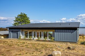 Ein modernes Haus mit Metall-Dach, großen Fenstern und einem Rasen.
