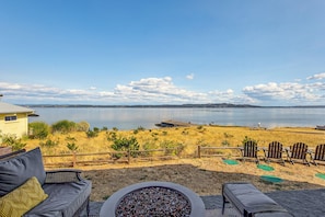 Eine Terrasse mit Gartenmöbeln mit Blick auf einen See, einem Holzzaun und einer entfernten Uferlinie.