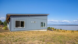 Une maison moderne avec de grandes fenêtres et vue sur l’eau.