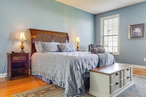 Une chambre à coucher avec un lit, des tables de chevet, une chaise, une commode et une fenêtre.