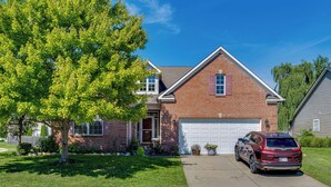 A two-story house with a brick facade, a front garage, and a parked SUV. - Modern Home w/ Private Deck & Yard in Indianapolis (Indianapolis)