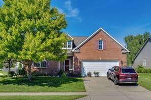 A two-story house with a brick facade, a front garage, and a parked SUV. - Modern Home w/ Private Deck & Yard in Indianapolis (Indianapolis)