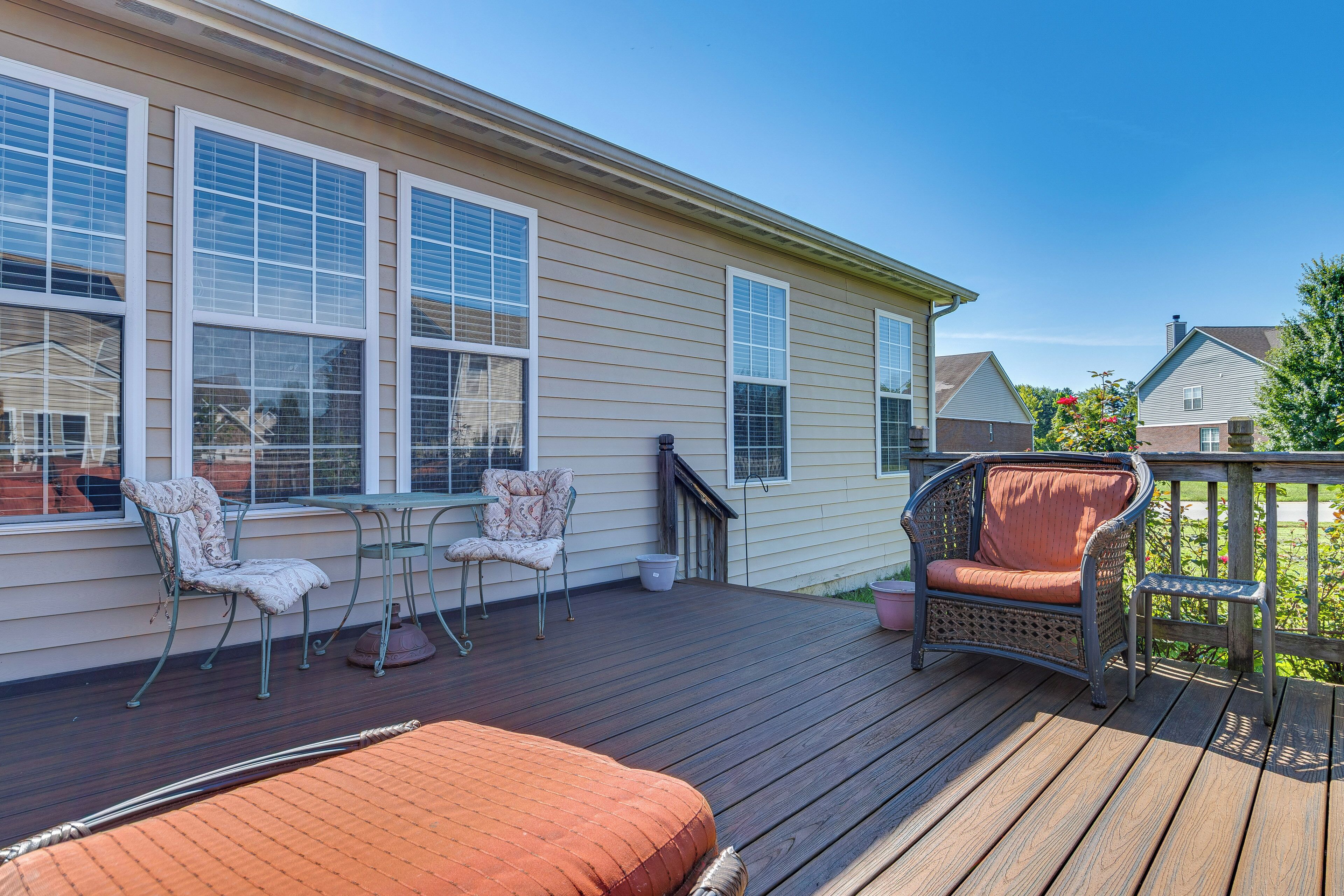 A covered deck with outdoor furniture, including chairs and a table, and a brick planter.