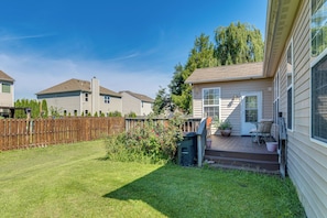 A residential property with a fenced backyard, a porch with outdoor seating, and a clear sky. - Modern Home w/ Private Deck & Yard in Indianapolis (Indianapolis)