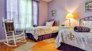 A bedroom with two beds, a rocking chair, a bedside table with a lamp, and a window with curtains. - Modern Home w/ Private Deck & Yard in Indianapolis (Indianapolis)