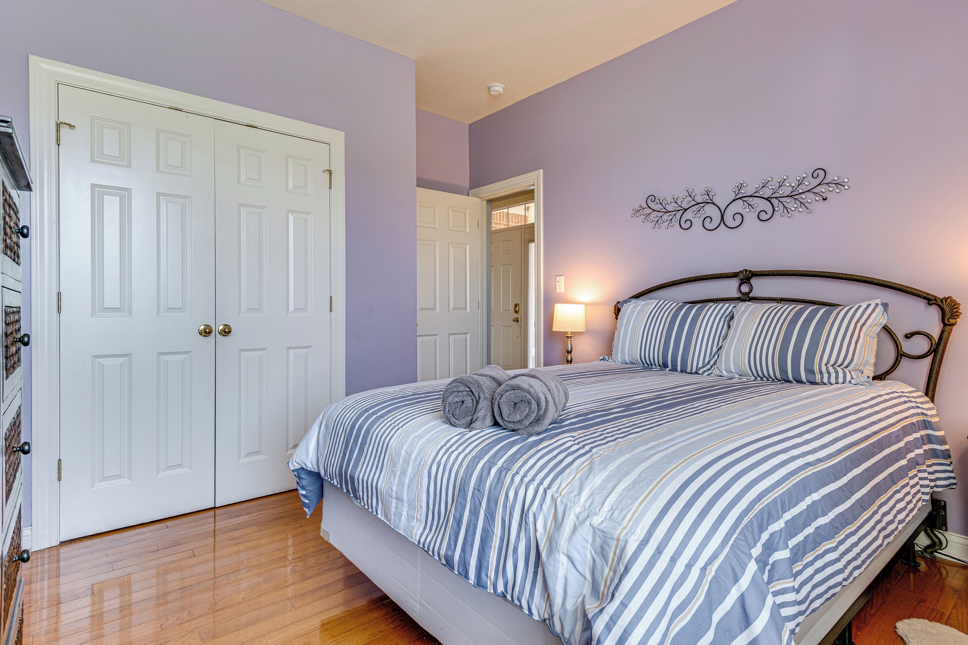 Un dormitorio con cama, mesita de noche, lámpara y un adorno en la pared.
