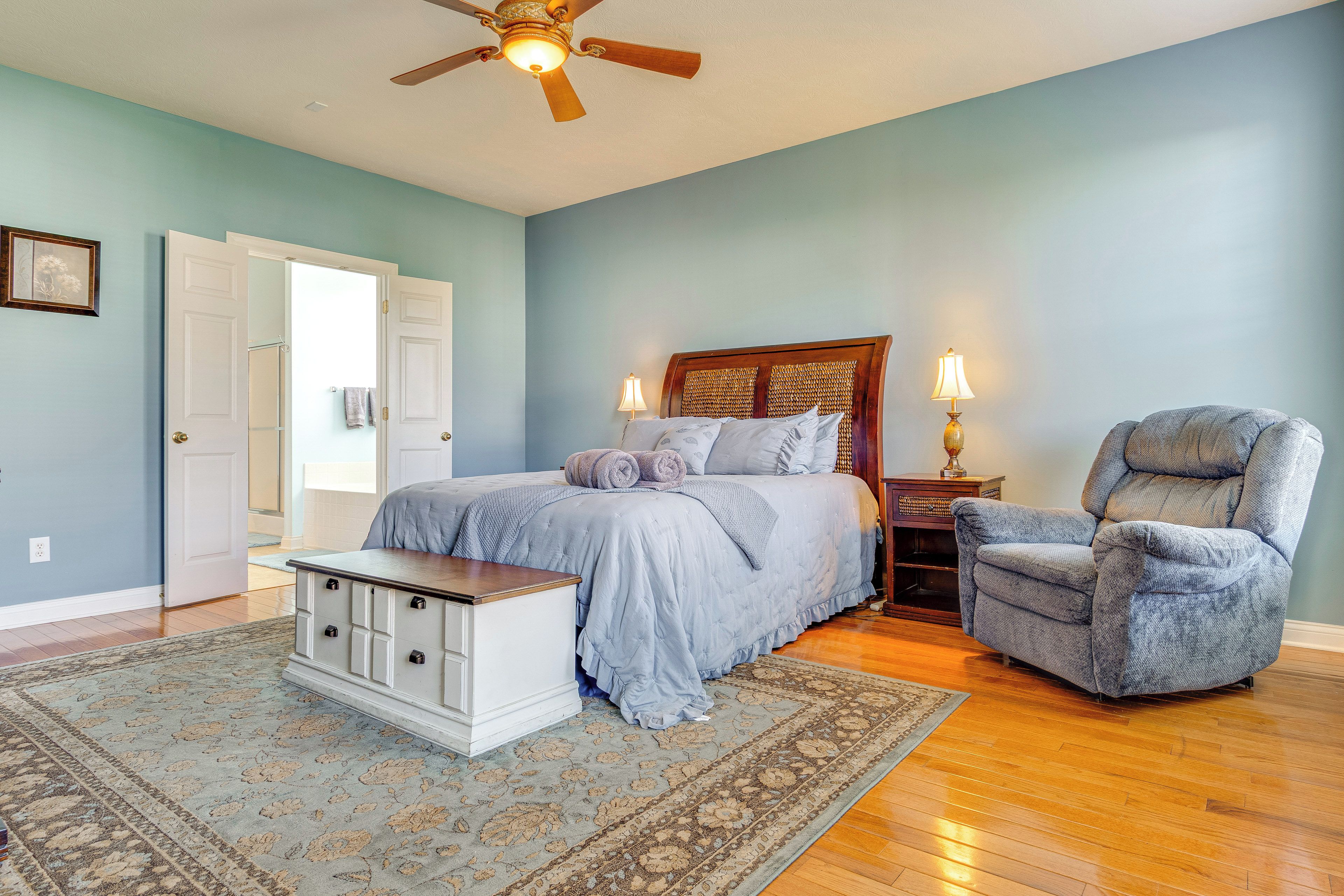 A bedroom with a bed, a chair, a nightstand, a dresser, and a ceiling fan.