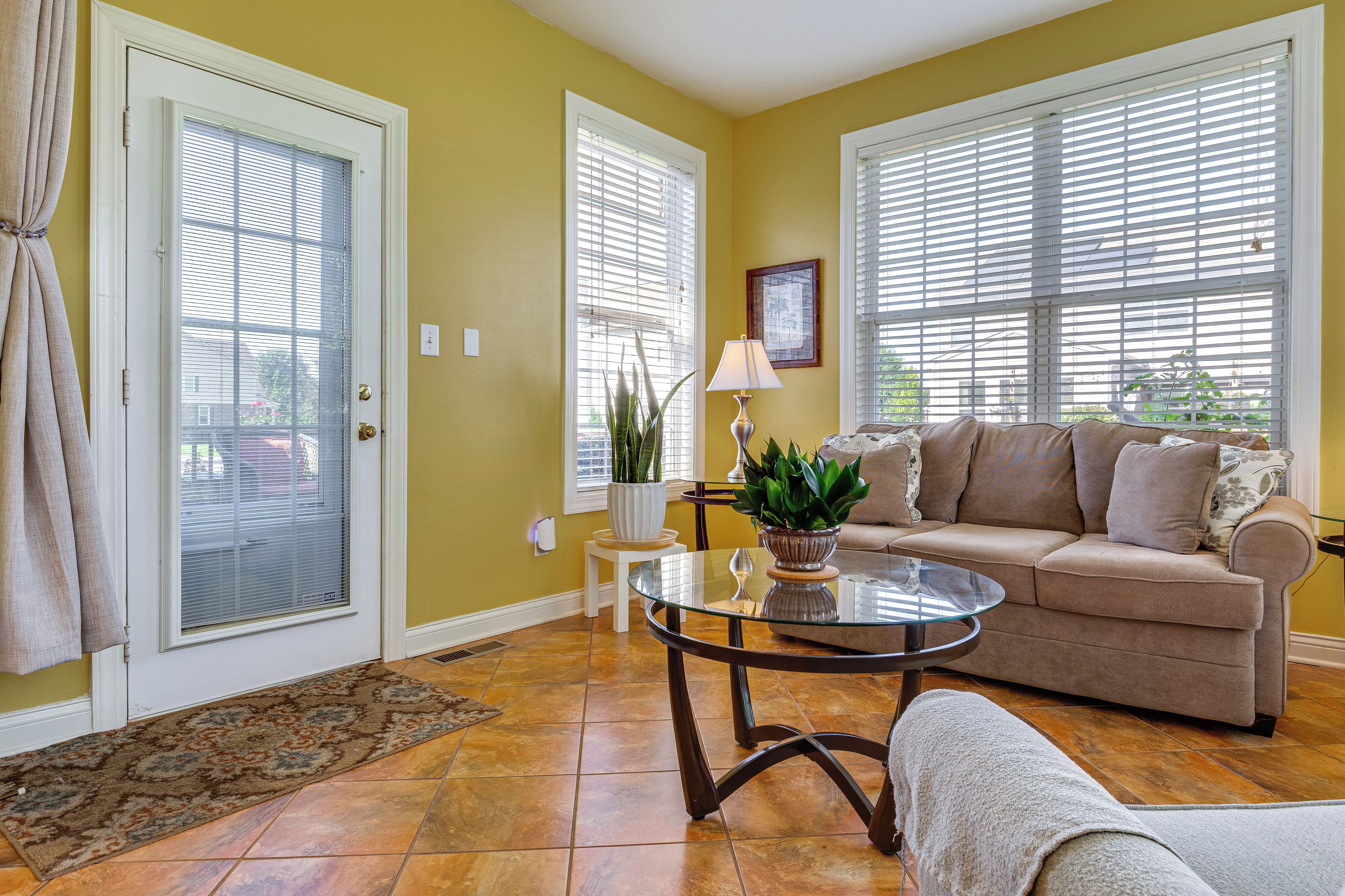 A living room with a beige sofa, a glass coffee table, and a potted plant.