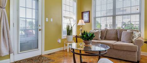A living room with a beige sofa, a glass coffee table, and a potted plant.