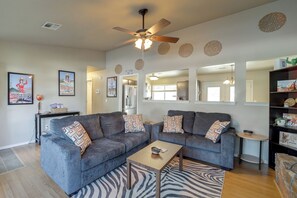 Ein Wohnzimmer mit zwei grauen Sofas, einem Holztisch und einem Teppich mit ZEBRA-Muster.