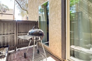 A barbecue grill on a patio with a wooden fence and a glass door. - Poolside Days! Condo 3 Mi to University of Arizona (Tucson)