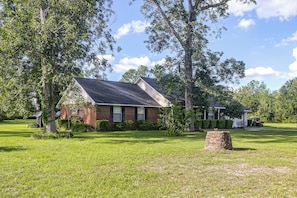 A two-story brick house with a sloped roof, surrounded by a well-maintained lawn and trees.