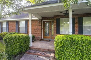 A residential house with a brick facade, a front porch, and a covered entryway.