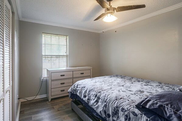 A bedroom with a bed, a nightstand, a dresser, a ceiling fan, and a window with blinds. - Fish, Swim & Soak: Rural Lakeland Retreat (Lakeland)