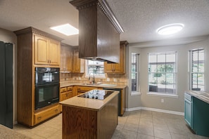 A kitchen with wooden cabinets, a black oven, and a central island.
