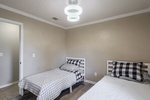 A bedroom with a single bed, a second smaller bed, a white ceiling light, and a door. - Fish, Swim & Soak: Rural Lakeland Retreat (Lakeland)