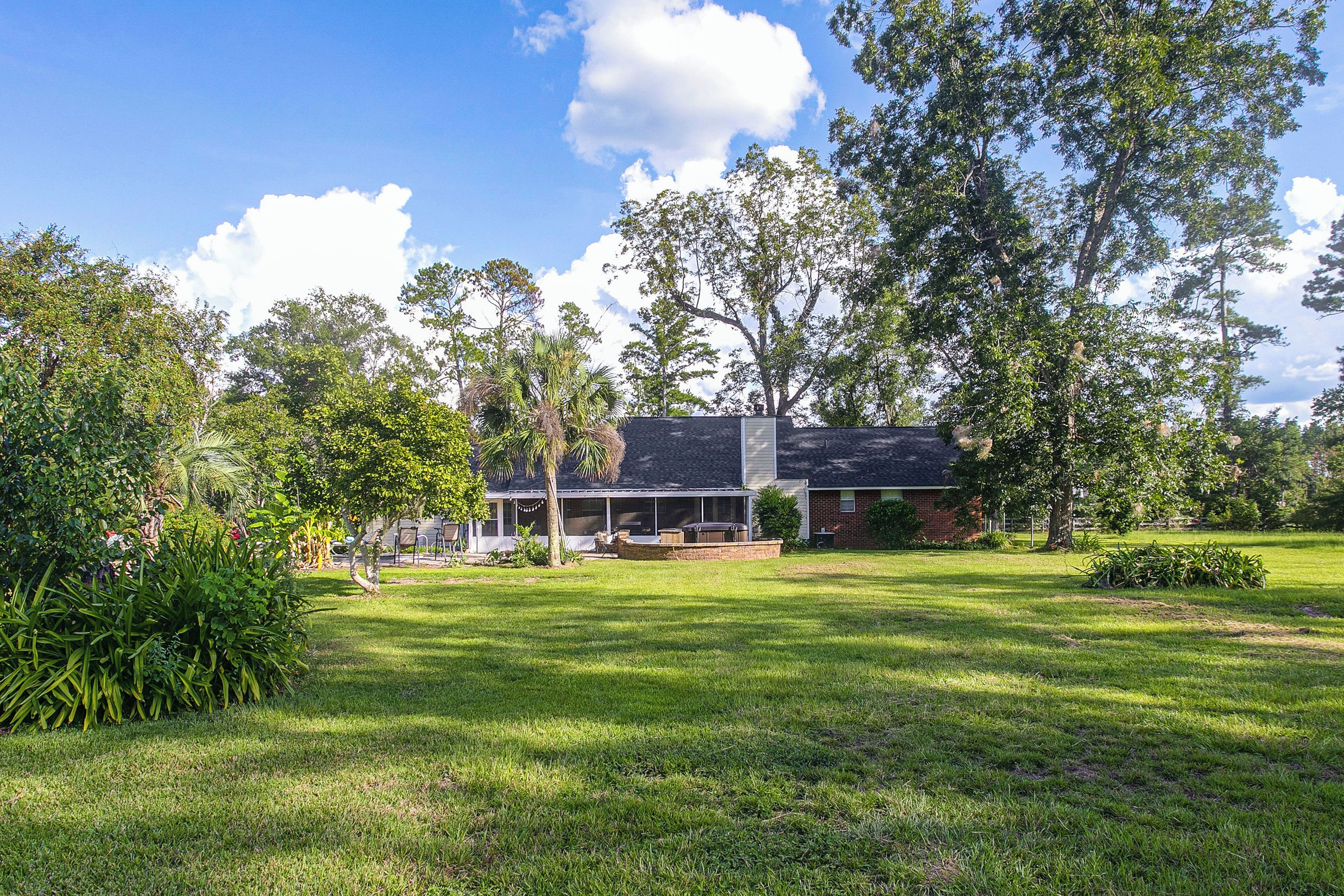 A residential property with a covered patio, a brick exterior, and a lawn.