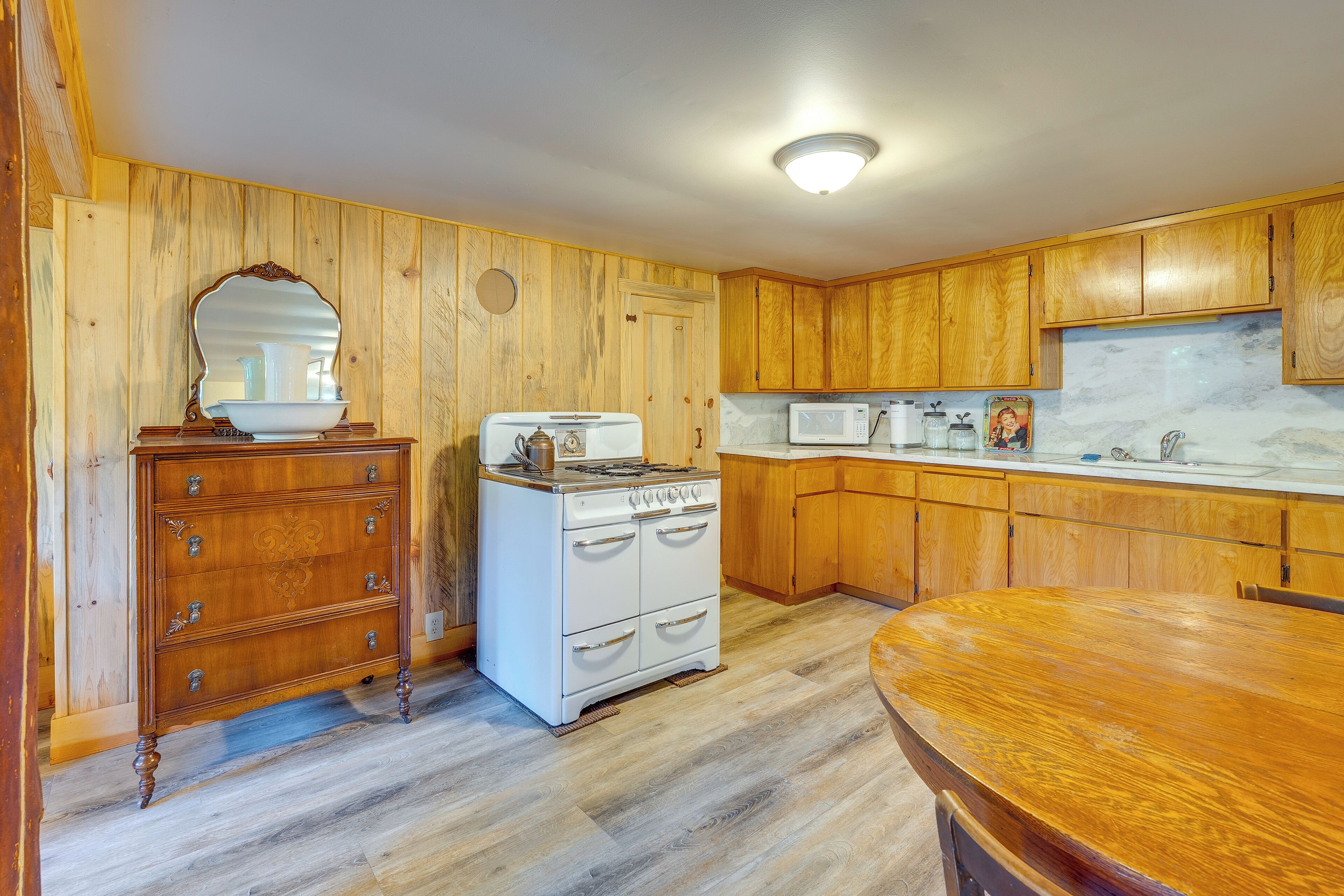Une cuisine avec des meubles de rangement en bois, une cuisinière, un four à micro-ondes et une table à manger en bois.