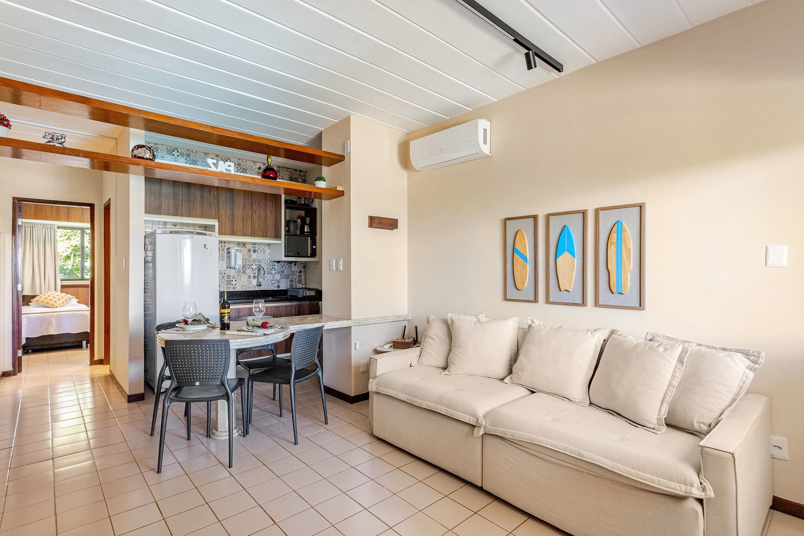 Eine moderne Küche mit Essbereich, einer Couch und drei gerahmten Surfbrettern an der Wand.