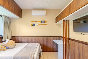 A hotel room with a bed, a television, and a wall-mounted air conditioning unit. - Guarajuba, 1-bedroom apartment near the beach (Camaçari)