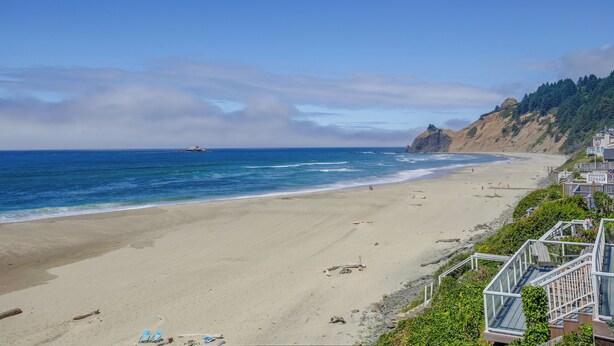 A beach with a clear sky, calm sea, and a rocky cliff with vegetation. - Direct Beach Access, 2 Mi to Chinook Winds Casino (Lincoln City)