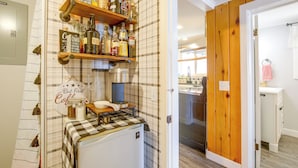 A kitchen with a coffee machine, a shelf with various bottles, and a sign with a humorous message. - Direct Beach Access, 2 Mi to Chinook Winds Casino (Lincoln City)